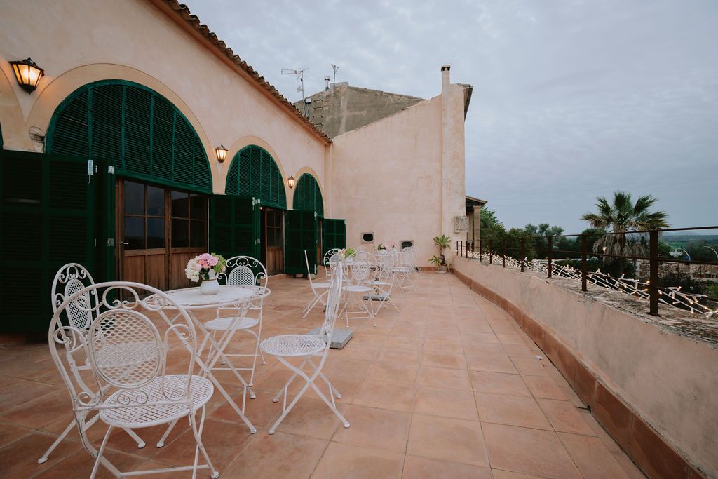 The arcaded terrace of Son Sant Andreu with green-painted arches and a tiled floor, looking out over open Mallorcan fields